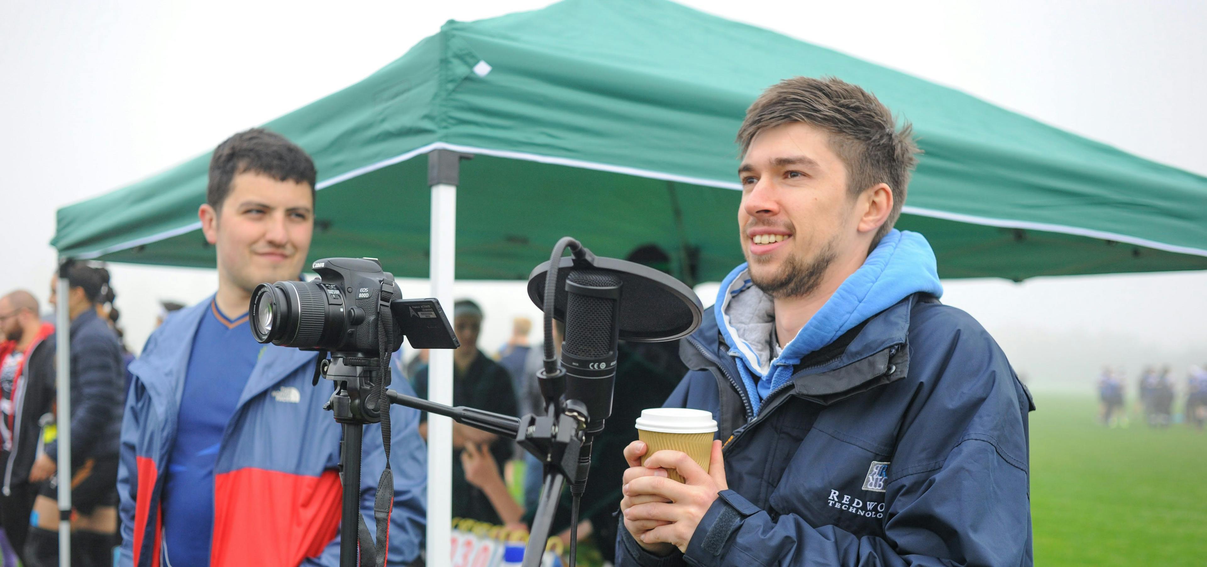 A camera operator (left) and a commentator (right) help capture the moment in a game of quadball on a foggy day.